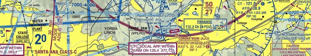 Click to Open Excerpt from a VFR sectional aeronautical chart highlighting Corona Municipal Airport (KAJO) and surrounding Southern California airspace, including radio frequencies, controlled airspace boundaries, and nearby landmarks.